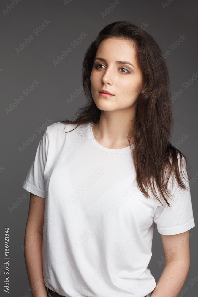 attractive female model four thirds view in blank white t-shirt and jeans isolated on gray background attractive female model four thirds view in blank white t-shirt and jeans isolated on gray background