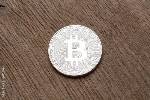 Close up of silver bitcoin on wooden background.