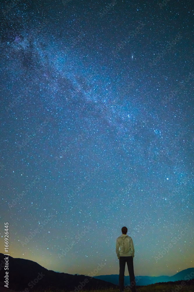 Fototapeta premium The man stand and look to the starry sky. night time
