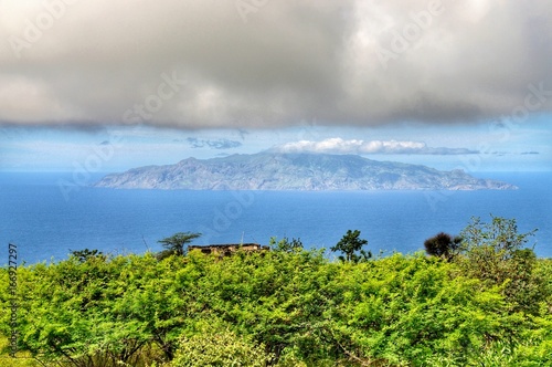 Island of brave at sea in between the clouds and trees as seen from sister island of Fogo in Cabo Verde