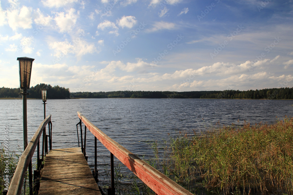 Naklejka premium The wooden footbridge on the shore of the lake