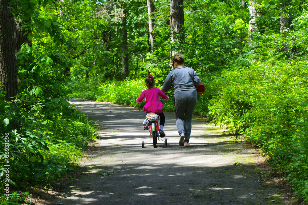 Dabushka and granddaughter ride a bicycle in the city park. May 28, 2017.