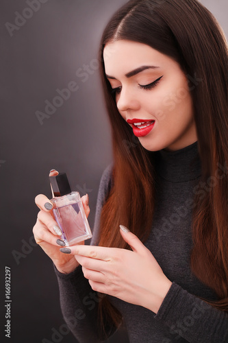 Young smiling woman spraing parfumes in the bathroom photo