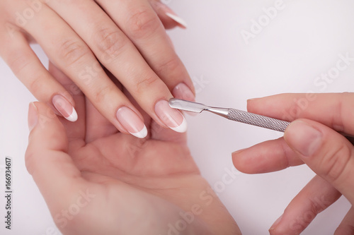 Closeup shot of a woman in a nail salon receiving a manicure by a beautician with cotton wool with acetone. Woman getting nail manicure. Beautician file nails to a customer photo