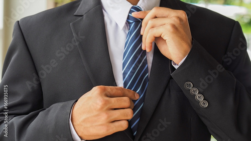 Canvas Print Businessman adjusting his tie with fitted suit for start working, blurred focus