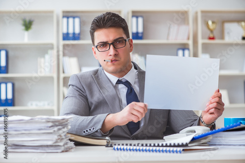 Businessman smoking at work in office holding a blank message bo