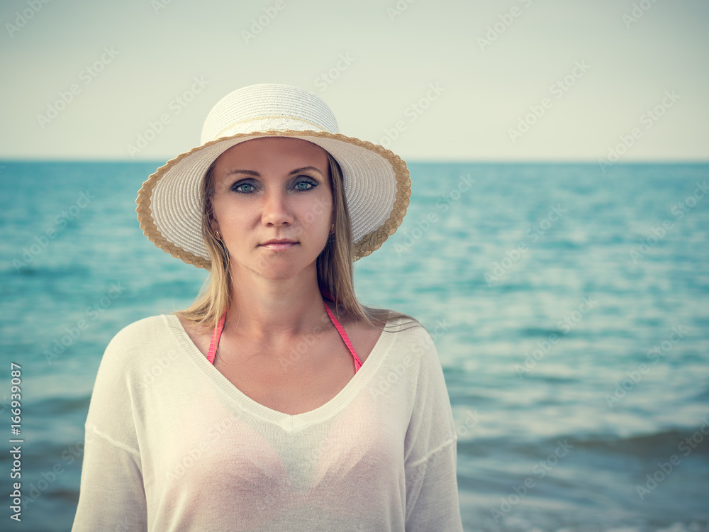 Beautiful middle-aged woman in hat on the beach.