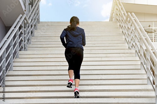 Young exercise woman running alone up stairs