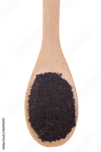 Black tea on a bamboo spoon, isolated on white.