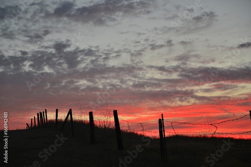 Silhouette of barbed wire fence over fiery sky at sunset