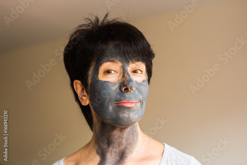 Cosmetology, spa, skin care and people concept - Woman applying Facial clay Mask. Beauty Treatments.