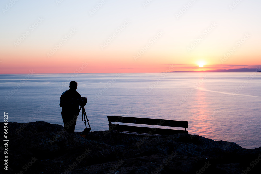 man photographer taking photos of sunset at the sea