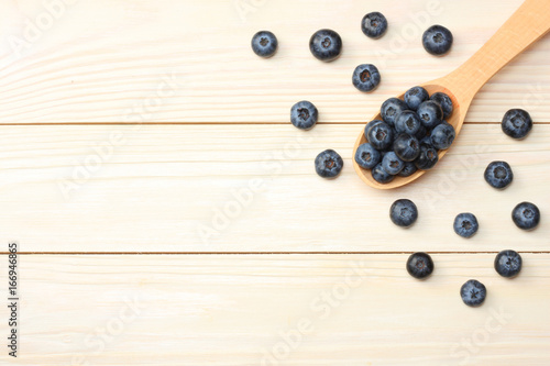 blueberries in wooden spoon on light wooden table background. top view with copy space