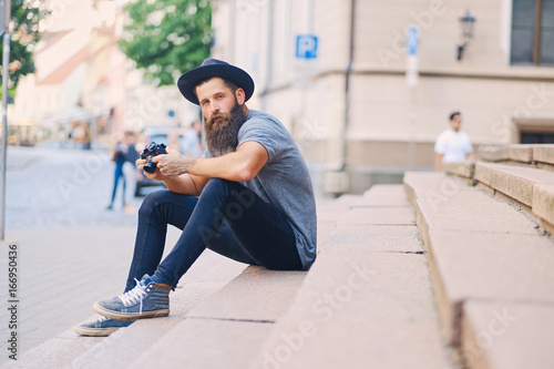 Street photographer sits on a step.