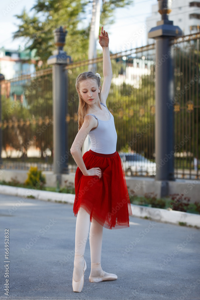 Young beautiful ballerina dancing outdoors in a park. Full length portrait. Young beautiful ballerina dancing outdoors in a park. Full length portrait.