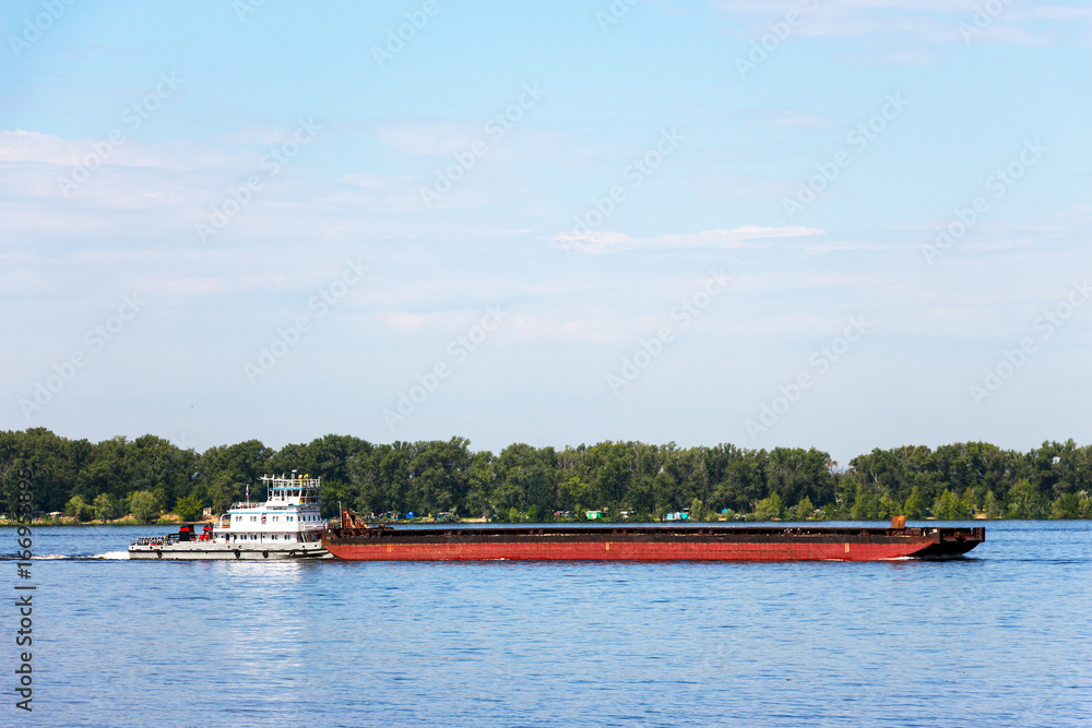 Cargo barge on the river. The barge is moved by a river tugboat