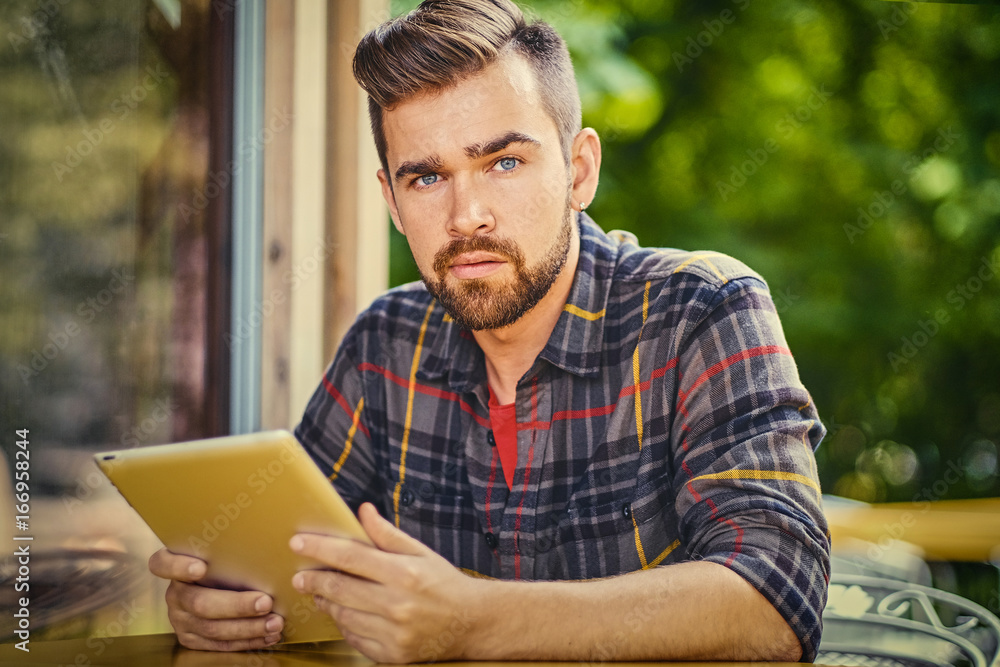 A man using a tablet PC in a cafe on a street. A man using a tablet PC in a cafe on a street.
