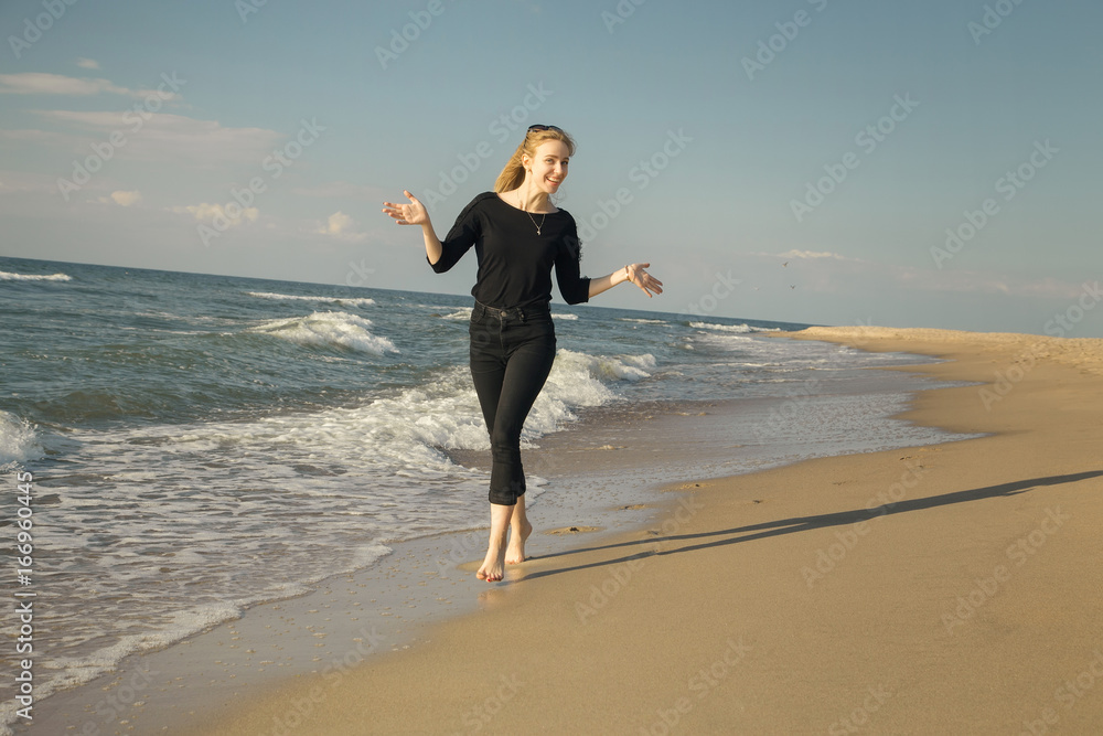 happy blond woman walking at sunny sea beach smiling, gesturing happy blond woman walking at sunny sea beach smiling, gesturing