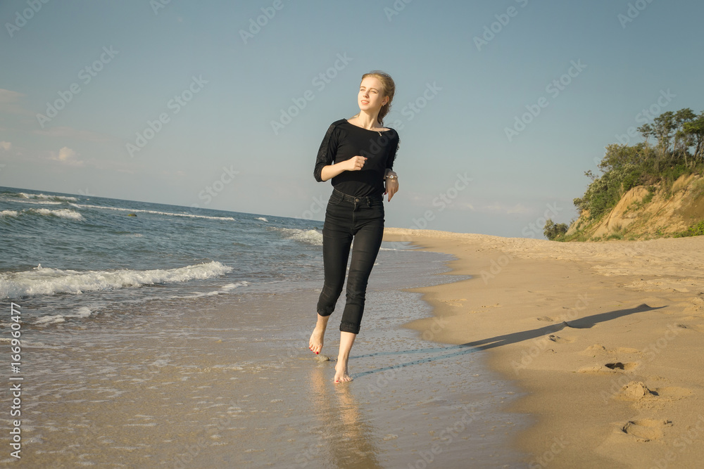 happy blond woman running at sunny sea beach smiling