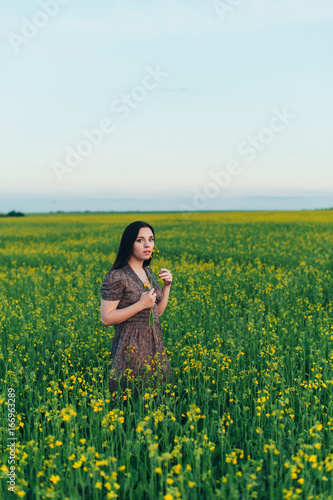 Beautiful young woman at sunset in the field