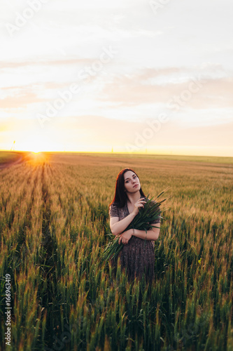 Beautiful young woman at sunset in the field