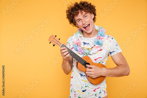 Attractive young man in summer clothes playing ukulele photo