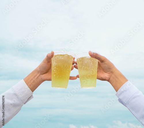 Celebration party, hands hold beverage beers with plastic glasses and cheer for success have beautiful sky as background