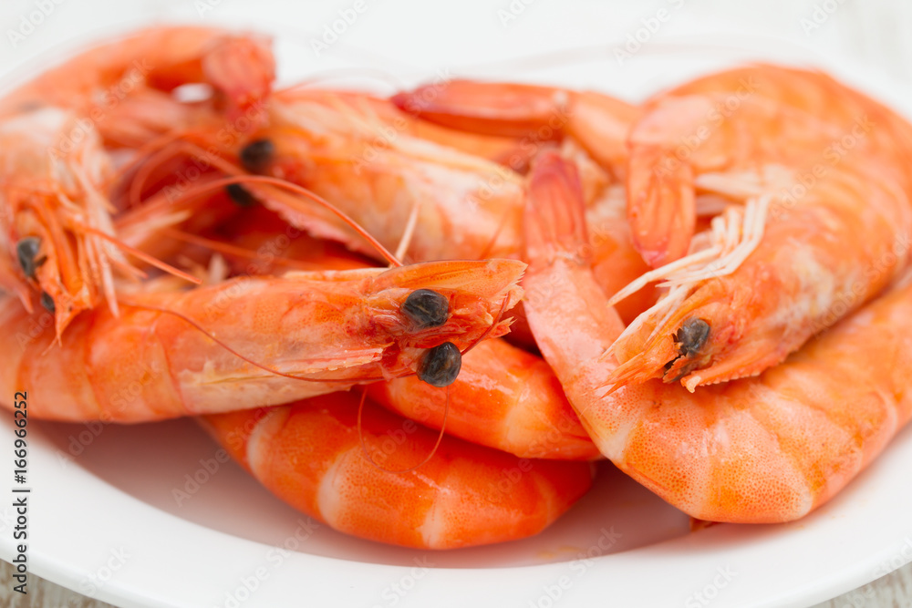 boiled shrimps on white dish on wooden background