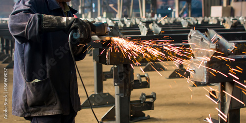 Worker grinding metal with angle grinder