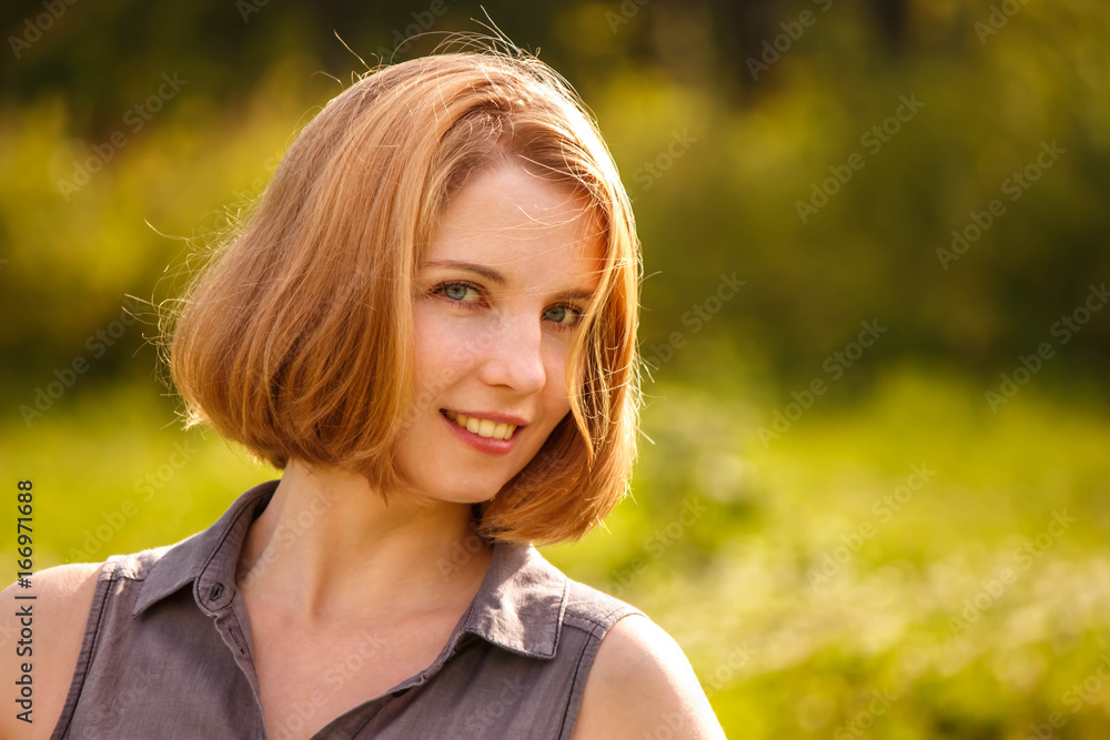 a young blonde girl happily smiling in the rays of the bright sun on green background a young blonde girl happily smiling in the rays of the bright sun on green background