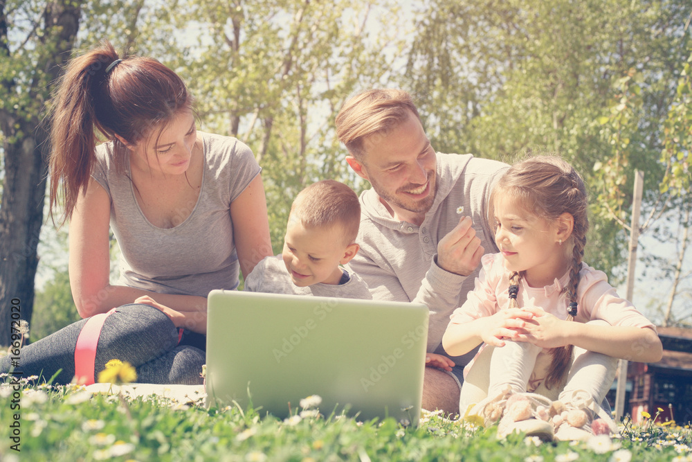 Family using laptop on the meadow. Family using laptop on the meadow.