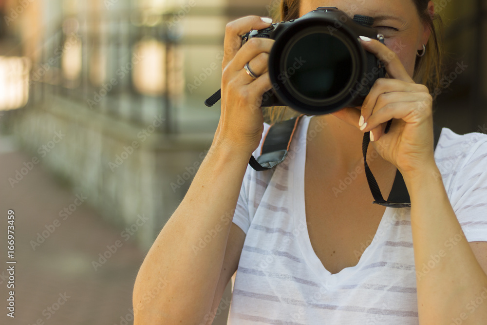Portrait of a photographer covering her face with the camera.. Photographer woman girl is holding dslr camera taking photographs. Focus on a woman's face