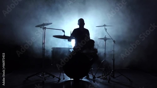 Energetic music in the performance of a professional drummer. Black background. Silhouette. Slow motion photo
