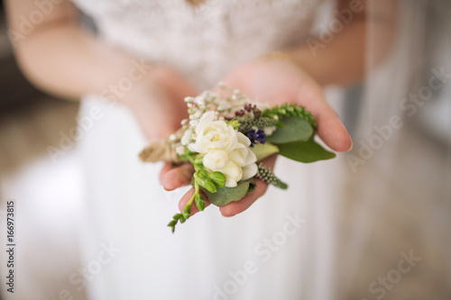 wedding boutonniere in the hands of the bride
