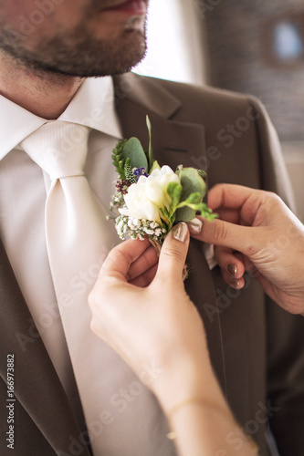 The bride clings to the bridegroom a boutonniere of real flowers