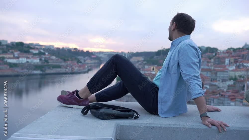 Young man admire view of Porto in Portugal sitting on ledge
Young man admire view of Porto in Portugal sitting on ledge