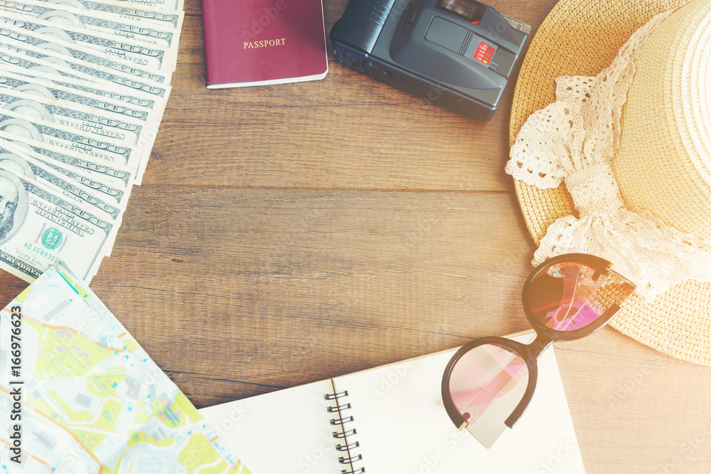 Travelling concept : Passport , notebook , map , U.S. dollar bills , camera , hat and eyeglasses Travelling concept : Passport , notebook , map , U.S. dollar bills , camera , hat and eyeglasses