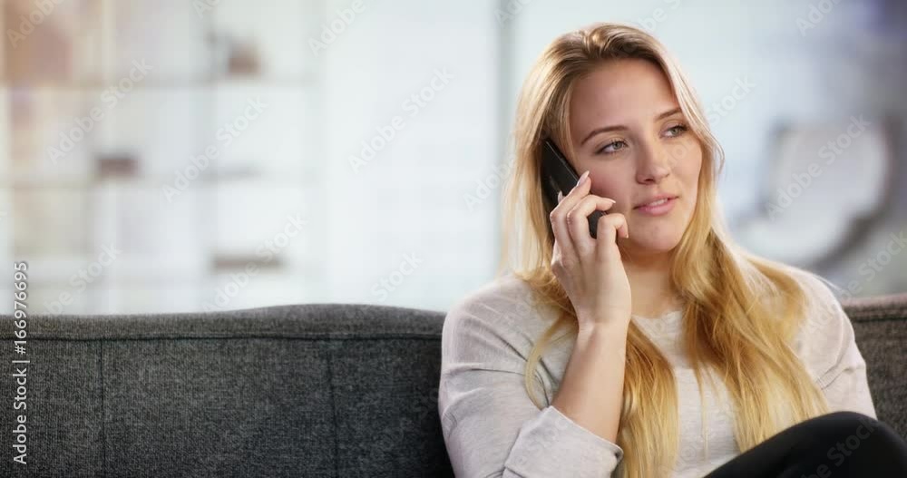 Happy woman talking on mobile phone sitting on couch at home Happy woman talking on mobile phone sitting on couch at home