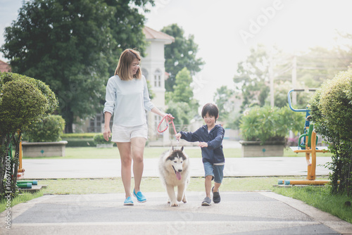 mother and son walking with a siberian husky don in the park