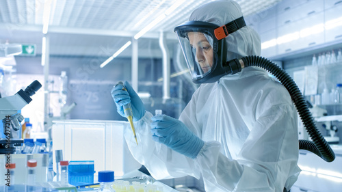 Medical Virology Research Scientist Works in a Hazmat Suit with Mask, She Uses Micropipette. She Works in a Sterile High Tech Laboratory, Research Facility.