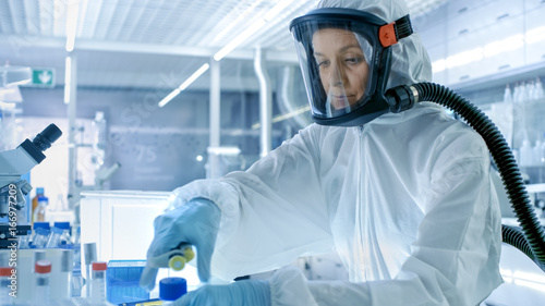 Medical Virology Research Scientist Works in a Hazmat Suit with Mask, She Uses Micropipette. She Works in a Sterile High Tech Laboratory, Research Facility.