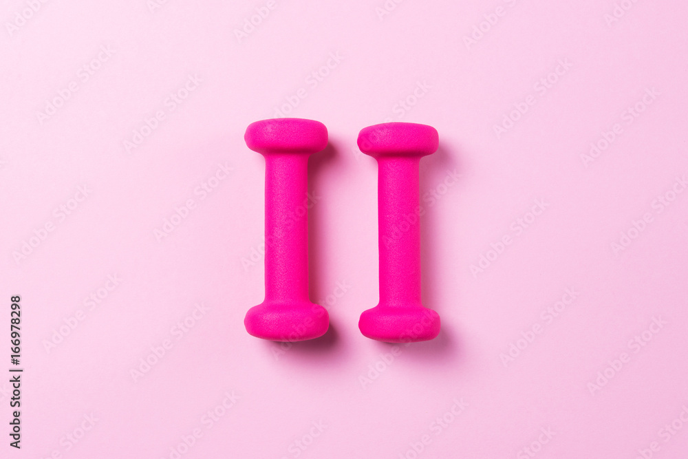Pink dumbbells on a pink background, minimalist concept, top view Pink dumbbells on a pink background, minimalist concept, top view