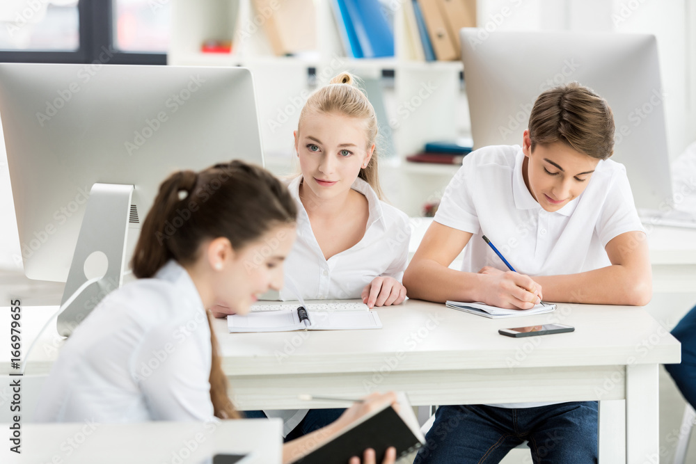 Obraz premium portrait of teenage girls and boy in white shirts during lesson in classroom