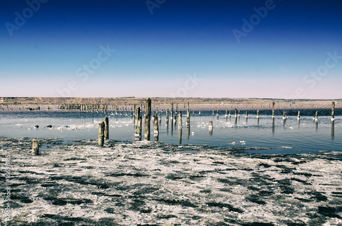 Beautiful salt lake with blue and pink water and wooden posts  natural landscape amazing background