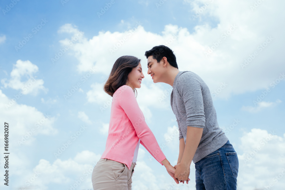 Young beautiful woman and asian man laugh against the dark blue sky with clouds Young beautiful woman and asian man laugh against the dark blue sky with clouds