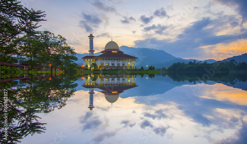 Mirror reflection of beautiful mosque during sunrise. photo