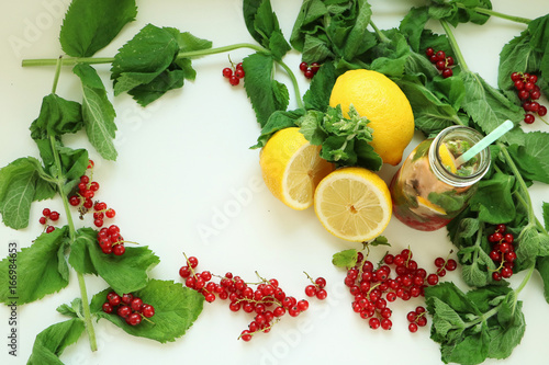 Fototapeta Naklejka Na Ścianę i Meble -  Frame of mint leaves, lemons and red currant berries and drink in bottle