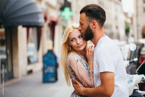Blonde girl and Hipster handsome man with beard hugging and kissing on the city streets