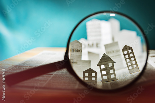 Foto Magnifying glass in front of an open newspaper with paper houses