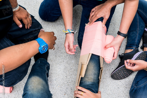 At First Aid Training Classroom, Students are trying to splint the leg of a patient's broken leg incident with cardboard and elastic bandage. photo